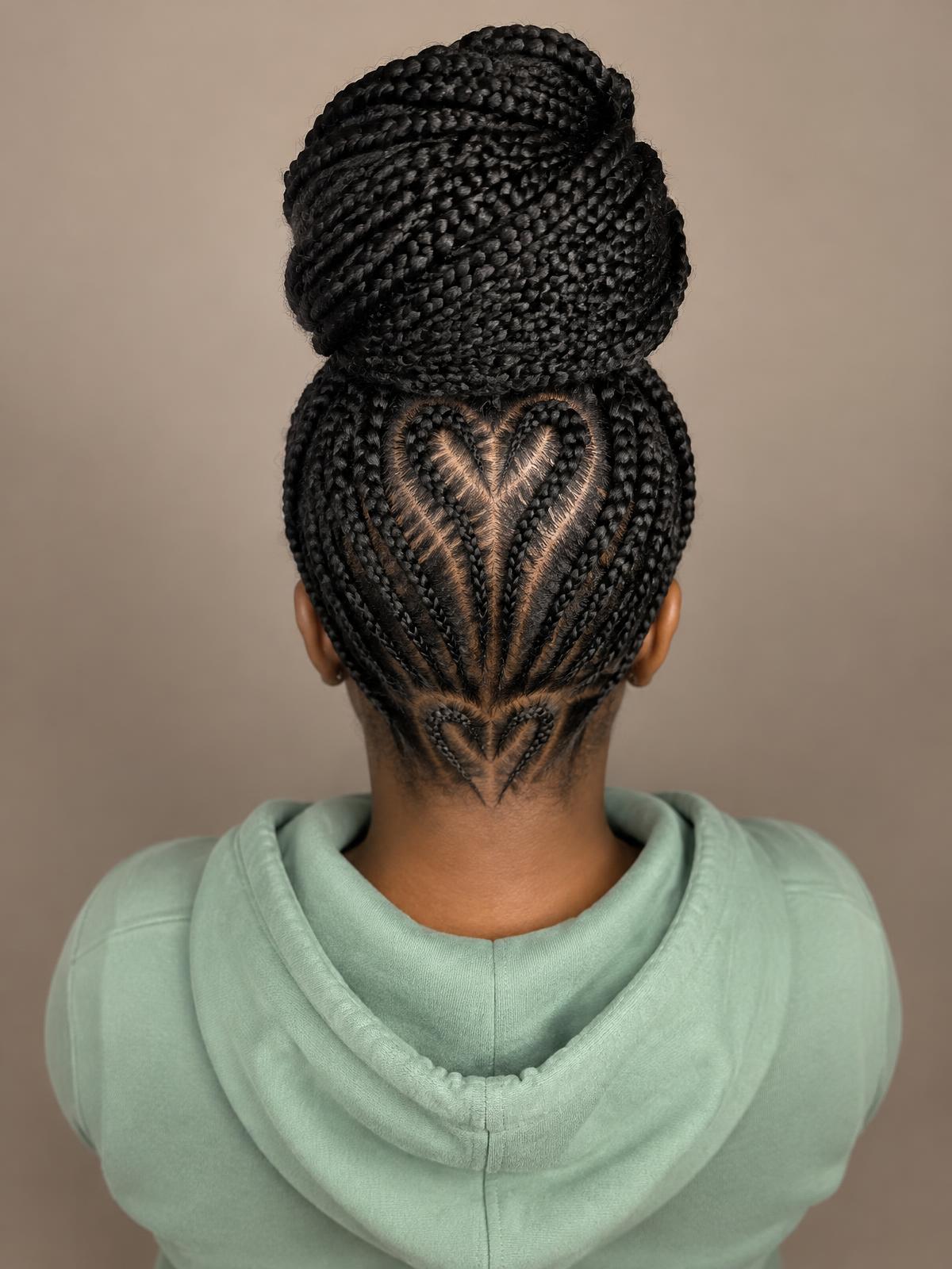Black box braids styled into a high bun with heart-shaped cornrow partings at the back, styled at Dixa Hair & Beauty Salon